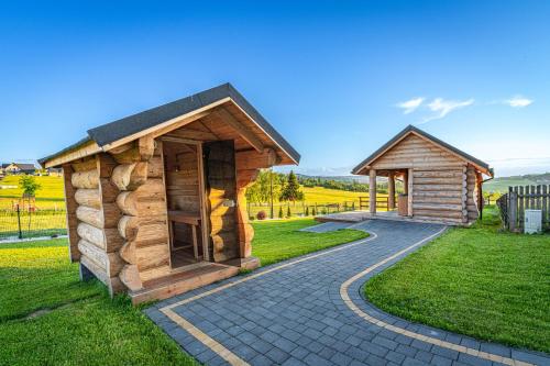 two small wooden buildings sitting on a grass field at Osada Szaflary in Szaflary