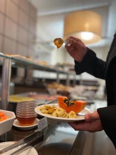 a person holding a plate of food with a spoon at Santa Catarina Plaza Hotel in Canoinhas