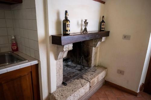 Una cocina con una chimenea de piedra con botellas encima. en Il Borgo di Mattia, en Cerreto di Spoleto
