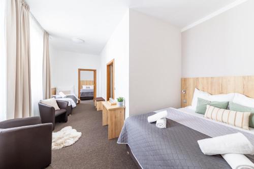 ein Schlafzimmer mit 2 Betten, einem Sofa und einem Stuhl in der Unterkunft Hotel Sněžné in Sněžné