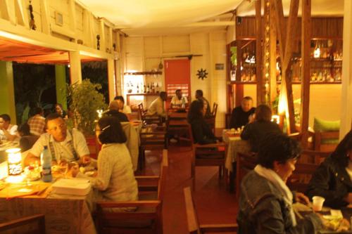 a group of people sitting at tables in a restaurant at Idylle Beach in Sainte Marie
