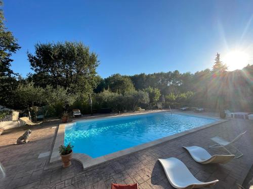 - une piscine avec 2 chaises blanches à côté dans l'établissement Les bergeries de DANIELLE, à Draguignan