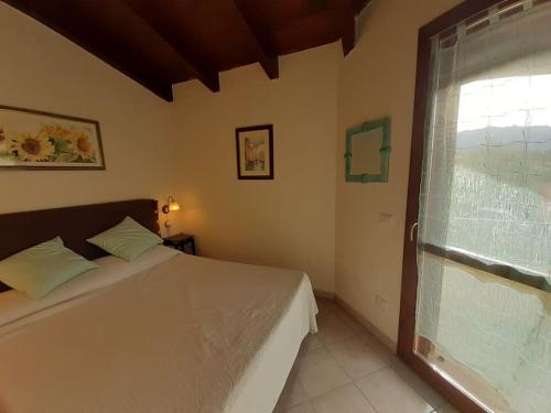 Un dormitorio con una cama blanca y una ventana. en Casa Costa Rei Villasimius, en Olìa Speciosa
