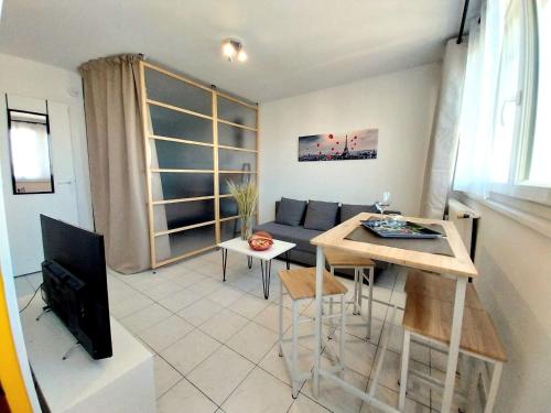 un salon avec un canapé et une table dans l'établissement Studio lumineux 3 min Gare Houilles - RER A, Ligne L et J, à Houilles