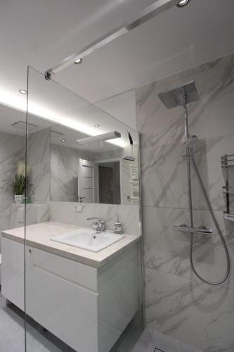 a white bathroom with a sink and a shower at Solaris Darłówko Premium Emilia Strupiechowska in Darłowo
