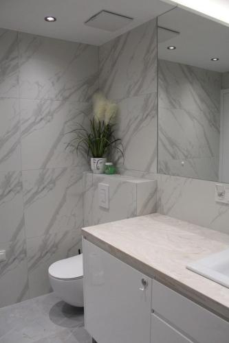 a white bathroom with a toilet and a sink at Solaris Darłówko Premium Emilia Strupiechowska in Darłowo