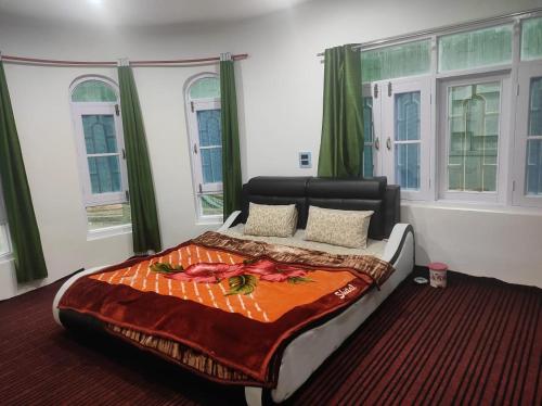 a bedroom with a bed with an orange blanket on it at New Delight Hotel in Kanzalwan