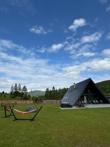 a building with a hammock in a field with a house at Treeline Cabins in Cădăreşti