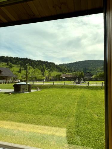 a view of a large grassy field from a window at Treeline Cabins in Cădăreşti