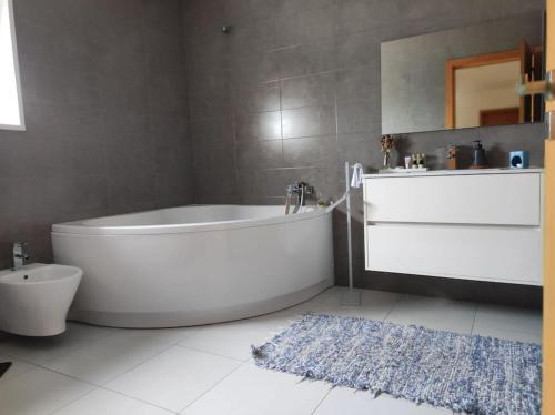 a bathroom with a tub and a toilet and a rug at Balutinha's house in Barcelos