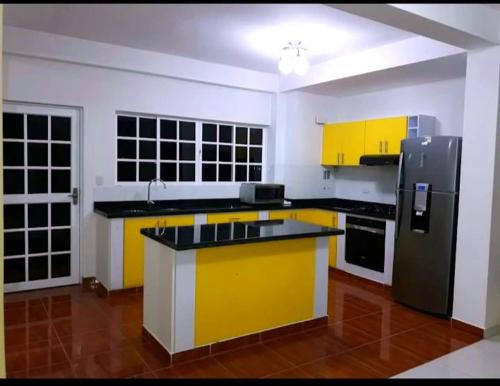 a kitchen with yellow cabinets and a black refrigerator at Finca Hotel el Amanecer in Quimbaya