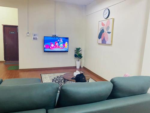 a living room with a couch and a tv on a wall at Selesa Homestay , Tingkat 1 di Bandar Jeli in Jeli