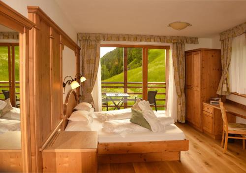 a bedroom with two beds and a large window at Hotel Fanes in Selva di Val Gardena