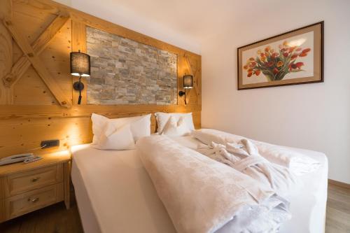 a bedroom with a white bed with a brick wall at Hotel Fanes in Selva di Val Gardena