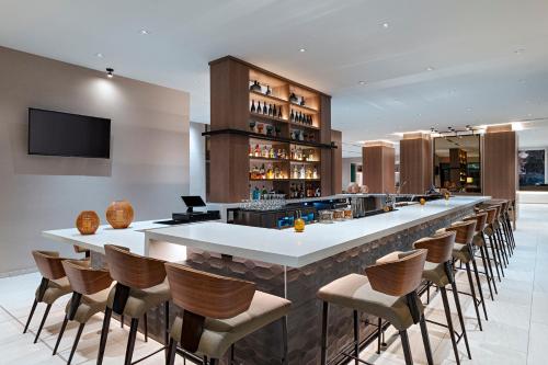 a bar with a bunch of stools in a room at AC Hotel by Marriott Waco Downtown in Waco