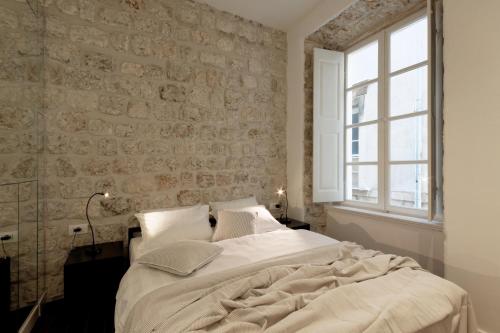 a white bed sitting in a room next to a window at Apartments Eleganca, crypto payment accepted in Dubrovnik