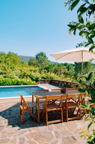 a table and chairs with an umbrella next to a pool at Just Like Home - Casa da Raposa in Caminha
