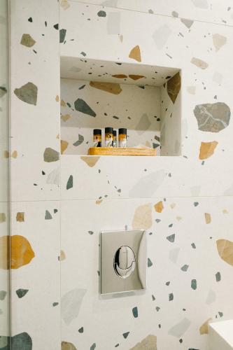 a bathroom with a rock wall with a shelf with three jars at Aquarama Suites in Iraklitsa