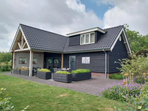 a house with a black roof and some plants at Vrijstaand vakantiehuis Weideblik in Biezenmortel