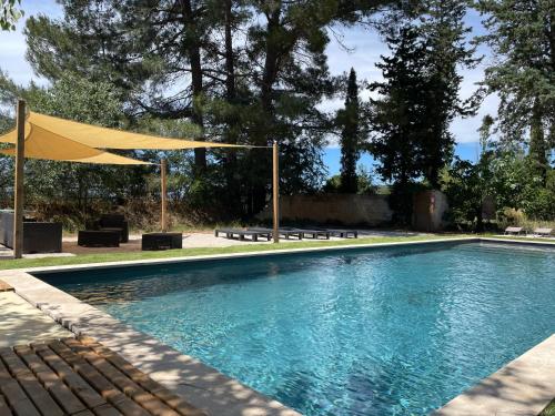 une piscine avec un parasol jaune et des bancs dans l'établissement Superbe annAix de villa, à Aix-en-Provence