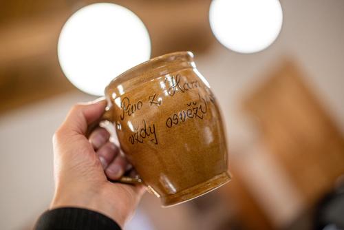 a person holding a coffee cup with writing on it at Hamr Divci Kamen in Křemže