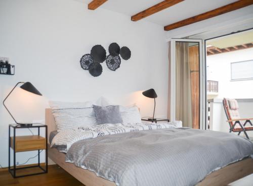 a bedroom with a white bed with a clock on the wall at swissme - modernes Studio mit Balkon & Parkplatz & Netflix in St. Moritz