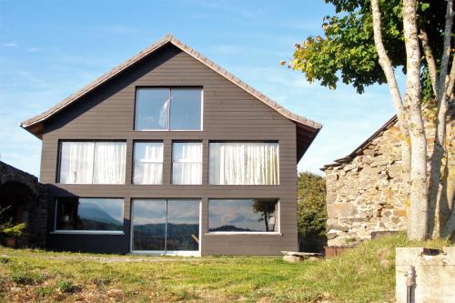 Cette maison est dotée de grandes fenêtres et d'un mur en pierre. dans l'établissement La Grange de l'Ardeyrol, à Saint-Clément