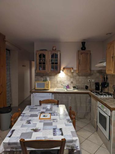 - une cuisine avec une table, des chaises et un comptoir dans l'établissement Pitchoun Oustaou du Champsaur, à La Fare-en-Champsaur