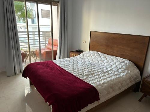une chambre avec un grand lit avec une tête de lit en bois dans l'établissement Charmant appartement à 5 min de la plage bouznika, à Bouznika