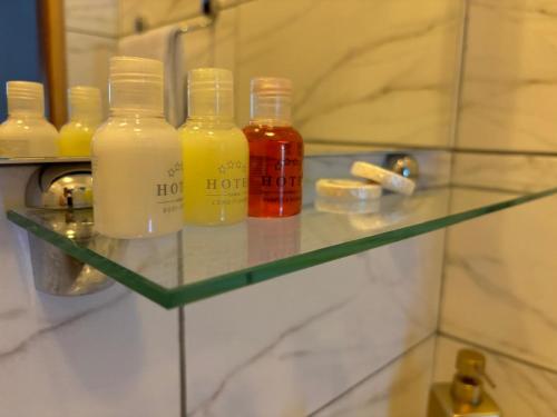 a glass shelf with four bottles of liquid at Riverside Resort Una in Bihać