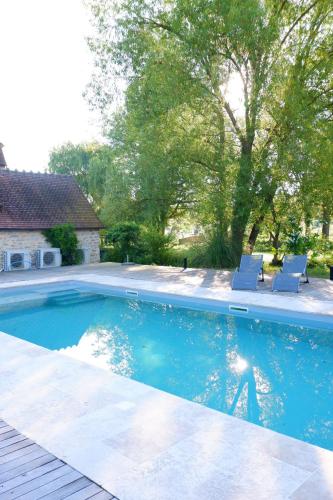 a swimming pool with two chairs in a yard at Moulin de Petoulle in Charenton sur Cher