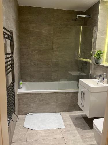 a bathroom with a tub and a toilet and a sink at Maplewood luxurious one-bed flat with free parking in St. Albans