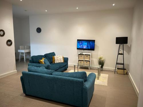 a living room with two blue couches and a flat screen tv at Maplewood luxurious one-bed flat with free parking in St. Albans