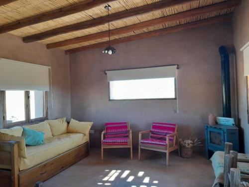 Casa rural con vistas a la Cordillera y Precordillera في Villa Pituil: غرفة معيشة مع أريكة وكرسيين