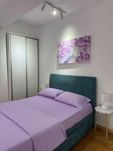 una camera da letto con un letto viola e un dipinto sul muro di TB apartment a Skopje