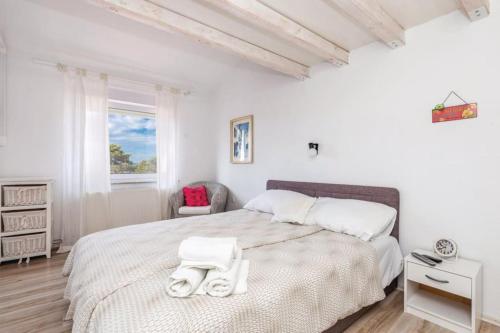a white bedroom with a large bed and a chair at Home sweet home- Rab in Barbat na Rabu