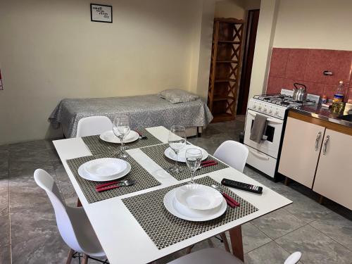 a kitchen with a table with plates and wine glasses at Departamentos Centro El Calafate in El Calafate