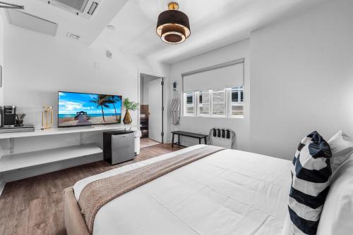 een witte slaapkamer met een groot bed en een flatscreen-tv bij Luxuri Suites 213 in Miami Beach in Miami Beach