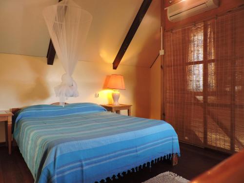 a bedroom with a bed with a blue blanket and a window at Villa Soleil D’été in Blue Bay