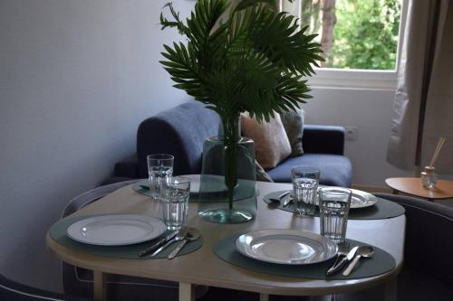 a table with plates and a vase with a plant on it at Élégant T2 à Bron, Tramway à 2min, Box Parking, 4Personnes in Bron