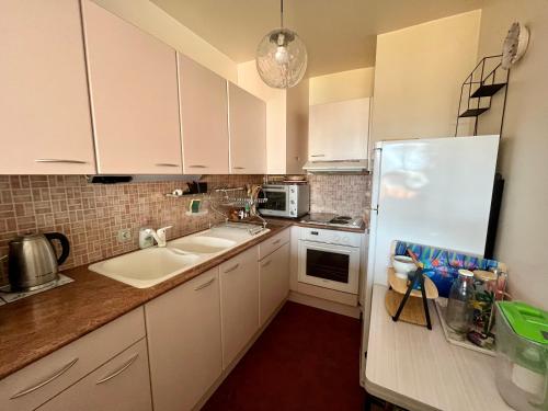 une cuisine avec des armoires blanches et un réfrigérateur blanc dans l'établissement Le Nid de Plage à 100 m de la mer, à Cabourg