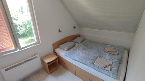 a small bed in a small room with a window at HauSol Vendégház in Gárdony