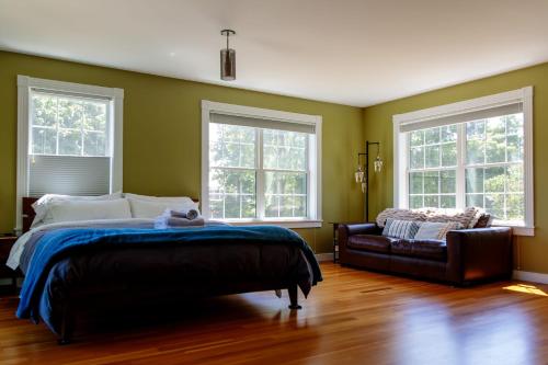 Un dormitorio con una cama y un sofá y ventanas. en Dwntwn home, Prvt Rooftop and Soaking Tub!, en Burlington