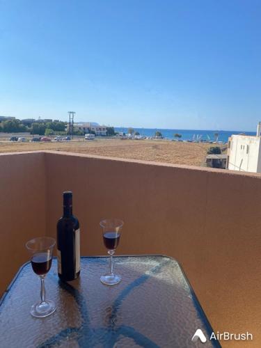 a bottle of wine sitting on a table with two glasses at Blue Sand Apartment in Analipsi