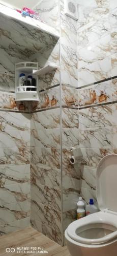 a bathroom with a toilet and a marble wall at Appartement Proche plage Bouznika Bouznika in Bouznika