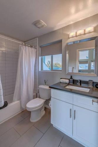 a white bathroom with a toilet and a sink at Mid Century Modern Game Room in Tucson