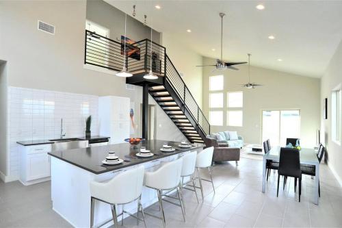 a kitchen with a bar with white chairs and a staircase at Mid Century Modern Game Room in Tucson