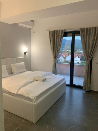 a white bed in a room with a large window at Hotel Albatros in Prizren