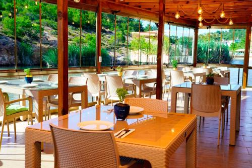 a restaurant with tables and chairs and windows at Olive Branch Hotel in Ayvalık
