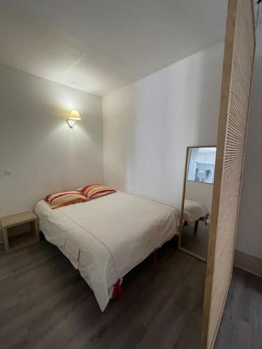 une petite chambre avec un lit et un miroir dans l'établissement Appartement - Dijon centre, à Dijon